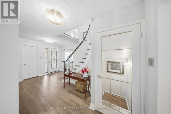 Foyer with light wood floors, a curved staircase, and decorative glass doors. - 1083 Ridge Valley Drive, Oshawa