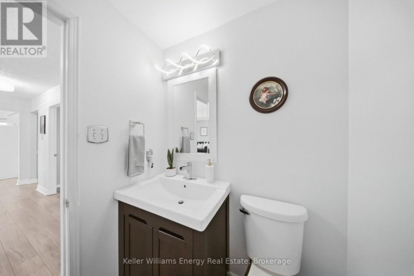 Powder room with a modern vanity, sink, toilet, and decorative wall mirror. - 1083 Ridge Valley Drive, Oshawa