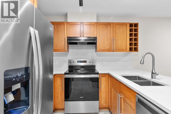 Corner view of a kitchen featuring a stainless steel stove and double sink. - 1083 Sunset Drive Unit# 211, Kelowna