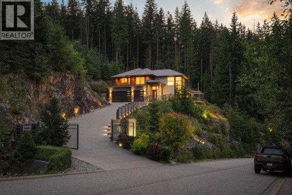 View of the property entrance with a gated driveway, stone accents, and outdoor lighting. - 1083 Uplands Drive, Anmore