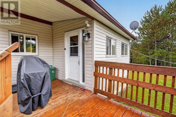Wooden deck with a covered grill, white door, and windows of a house exterior. - 1085 St. Cloud Road, Wahnapitae