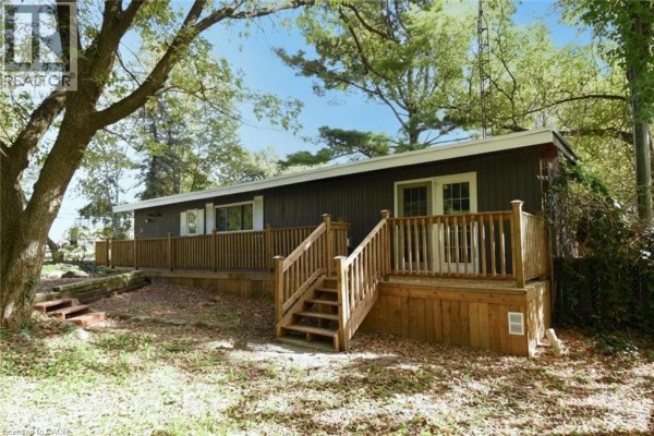 Side view of the mobile home featuring a wooden deck with stairs and glass doors. - 1085 W Concession 10 Concession W Unit# 99, Flamborough