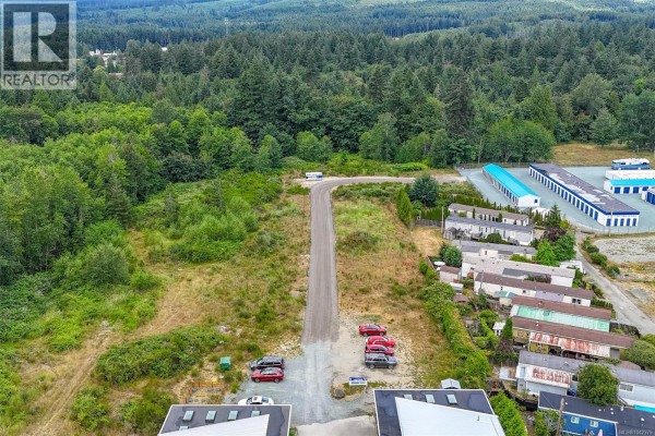 Aerial view of paved driveway leading to undeveloped land and surrounding buildings. - 10862 Chemainus Rd, Chemainus