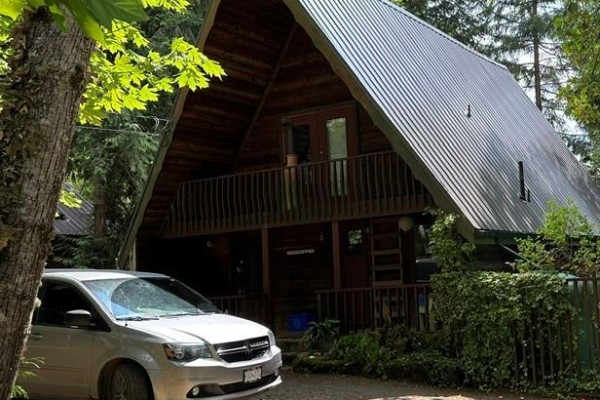 Silver minivan parked in front of a wooden A-frame house. - 1087 Chappel Pl, Gabriola Island