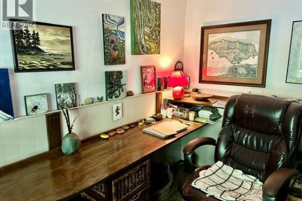 Desk with a leather office chair, artwork, and shelving with decor. - 1087 Chappel Pl, Gabriola Island
