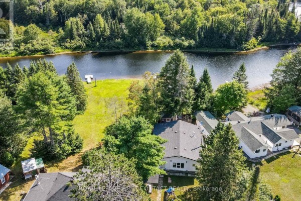 Gravel driveway leading through a wooded area towards a distant building. - 1088 Colony Road, Lake Of Bays