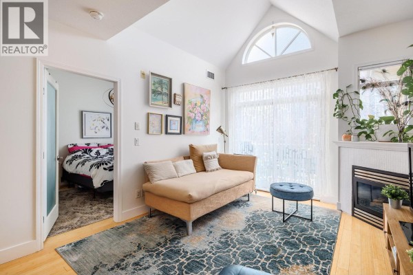 Cozy corner of the living room featuring a sofa, artwork, and a view into the bedroom. - 1088 Sunset Drive Unit# 247, Kelowna
