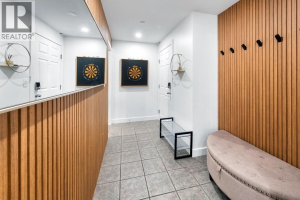 Hallway with wood slat accent walls, mirrored panels, and a grey bench. - 1088 Sunset Drive Unit# 352, Kelowna
