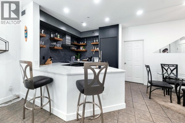 Hallway with two dartboards, wood slat walls, benches, and coat hooks. - 1088 Sunset Drive Unit# 352, Kelowna