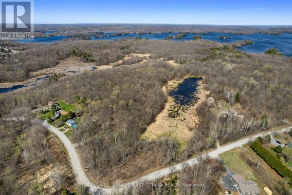 Aerial view of wooded land with red boundary lines and a large pond. - 1089 Wagner Road, Frontenac