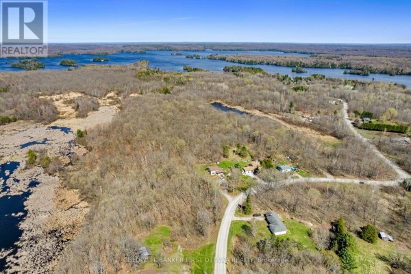 Aerial view of wooded land with houses, roads, and distant lakes. - 1089 Wagner Road, Frontenac