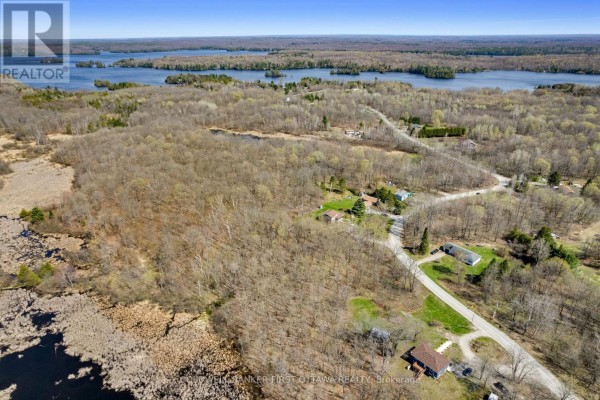 Aerial view of wooded land with houses, roads, and marshy water bodies. - 1089 Wagner Road, Frontenac