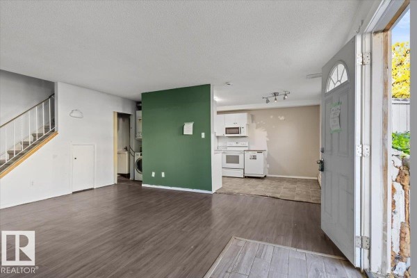 View of living room, kitchen, and laundry area with white appliances. - #108a 14520 52 St Nw, Edmonton