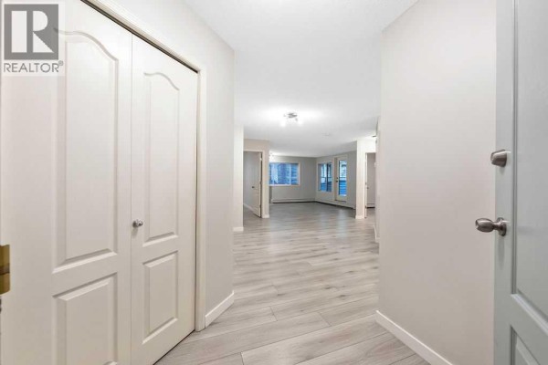 Interior hallway leading to an open-concept living area with double doors. - 109, 20 Sierra Morena Mews Sw, Calgary
