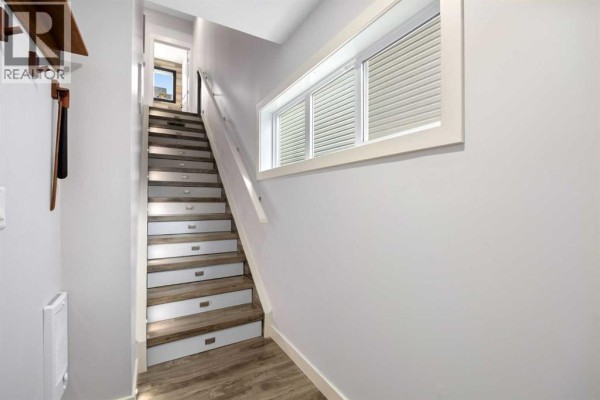 Covered balcony with a Weber grill, table, chairs, and a view of townhouses. - 109, 355 Nolancrest Heights Nw, Calgary