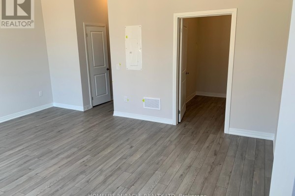 Interior view of a residential unit with a large window, balcony door, and an unfinished kitchen island with a sink. - 109 - 585 Colborne Street E, Brantford