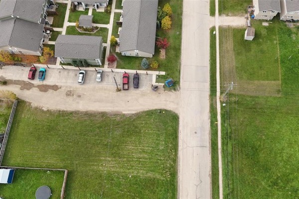 Aerial view looking down a street with parked cars, grass lots, houses, and an apartment complex on the left. - 109 1st Street, Swan River