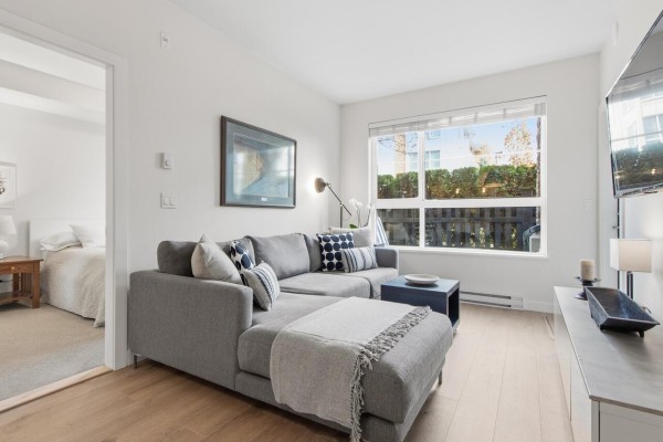 Cozy living area with large window, gray sofa, and view of greenery - 109 20829 77a Avenue, Langley