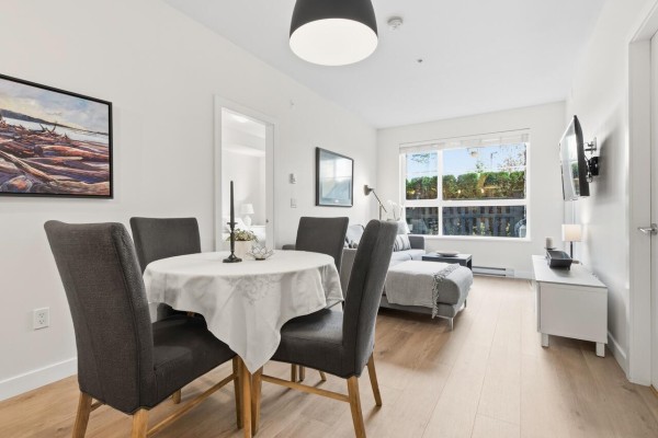 Dining area with round table, gray chairs, and adjacent living room - 109 20829 77a Avenue, Langley
