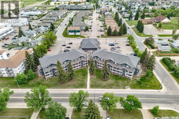 Aerial view of a grey apartment building complex with surrounding residential homes. - 109 515 28th Street E, Prince Albert