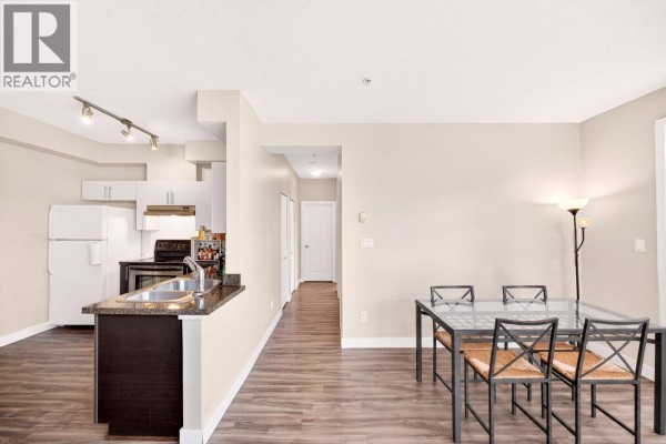 Kitchen and dining area with glass table, chairs, and view down a hallway. - 109 5692 Kings Road, Vancouver