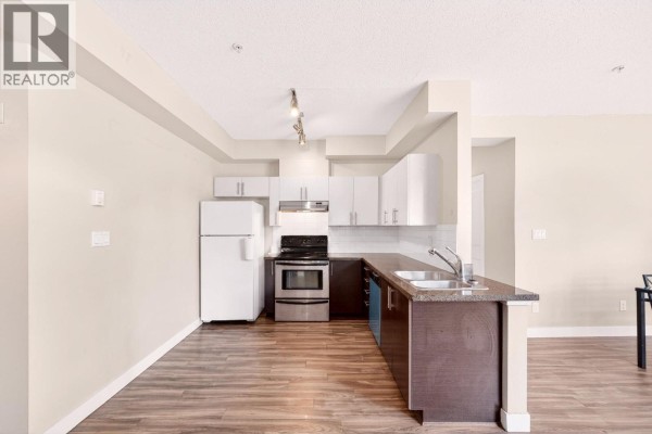 Kitchen with white cabinetry, stainless steel appliances, and dark wood island counter. - 109 5692 Kings Road, Vancouver