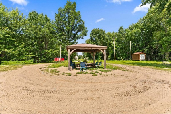 Aerial view of a wooded property with a house, a small red shed, and a large body of water. - 109 Ch. Boom, Pontiac