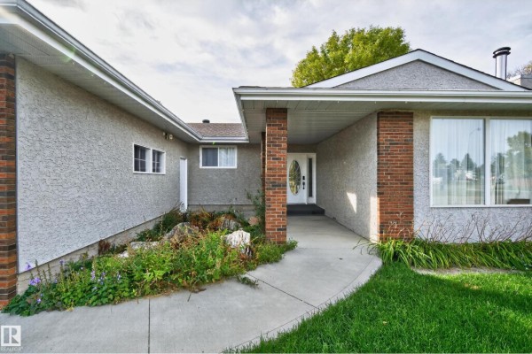 Concrete walkway leading to the front entrance of a bungalow with a glass storm door. - 109 Evergreen Cr, Wetaskiwin