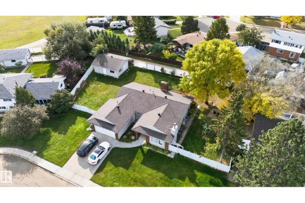 Aerial view of a bungalow with a white fence, detached garage, and mature trees. - 109 Evergreen Cr, Wetaskiwin