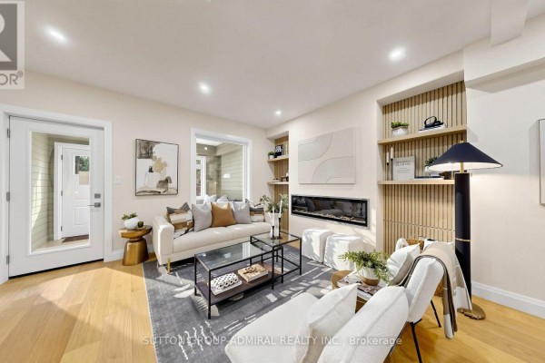 Open concept living area with light wood floors, fireplace, and stairs. - 109 Fermanagh Avenue, Toronto