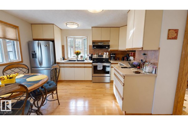Kitchen with light wood floors, stainless steel refrigerator, and cream-colored cabinetry. - 109 Galen Pl, Sherwood Park