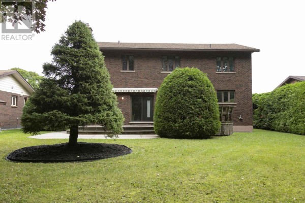 Backyard with mature trees, deck, and brick house - 109 Greenview Ln Sault Ste Marie