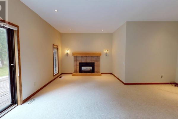 Living room with fireplace, large windows, and deck access - 109 Greenview Ln Sault Ste Marie