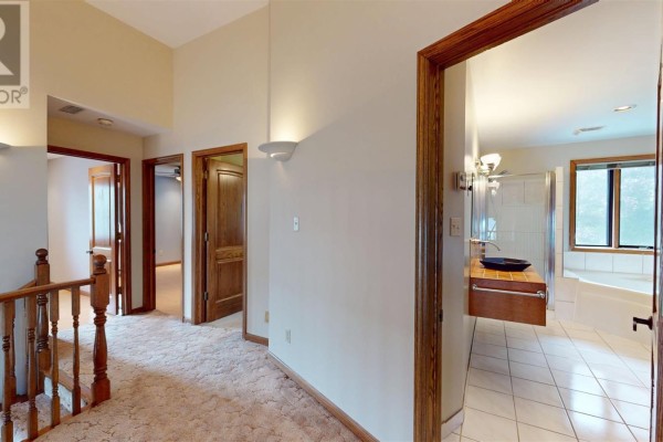 Hallway with wood banister, carpet, and doorways to bathroom with shower and tub - 109 Greenview Ln Sault Ste Marie