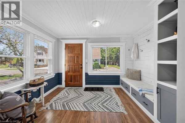 Interior view of a mudroom with wood floors, blue wainscoting, and built-in seating and storage. - 109 Hodgkins Avenue, Thorold