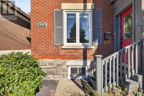 Close-up of the front door of a brick house with stone foundation and gray shutters. - 109 Lees Avenue, Ottawa