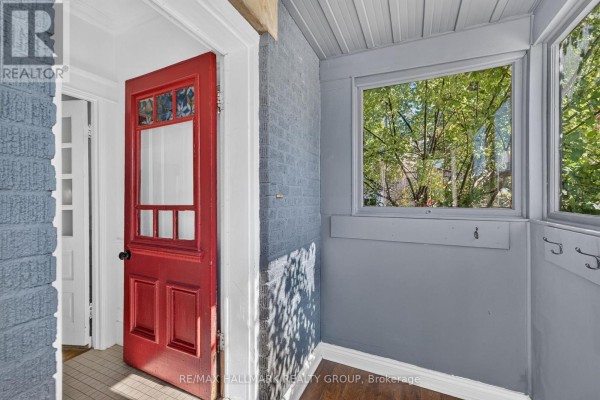 Interior view of a red front door and a window overlooking trees in a gray room. - 109 Lees Avenue, Ottawa