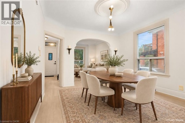 Dining room looking towards living room and front entrance, featuring a wood sideboard and oval table. - 109 Macaulay Street E, Hamilton