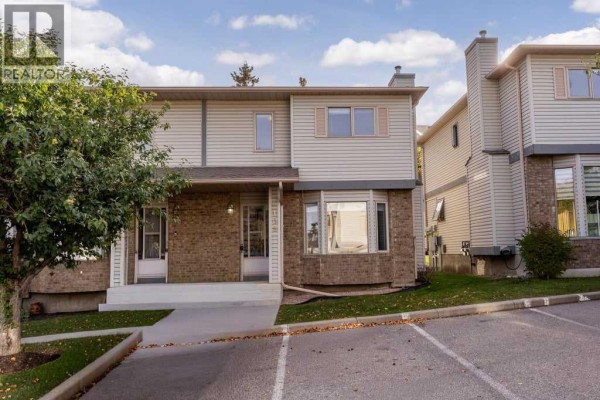 Exterior view of the townhouse from a slightly wider angle showing more parking and neighbouring units. - 109 Patina Park Sw, Calgary