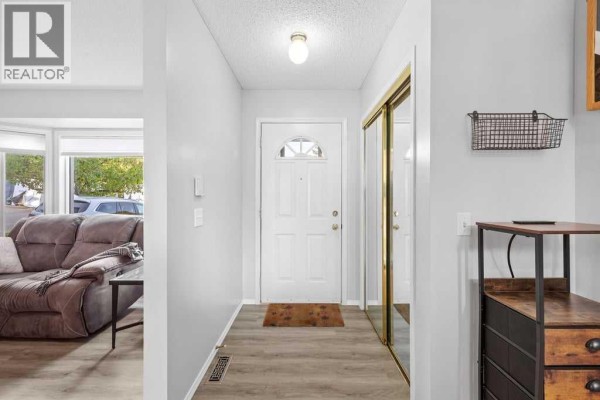 Entrance hallway with a white front door, mirrored closet, and light grey walls. - 109 Patina Park Sw, Calgary