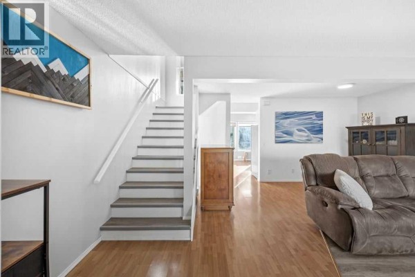 Interior view showing a staircase, a wooden cabinet, and a glimpse of the living area. - 109 Patina Park Sw, Calgary