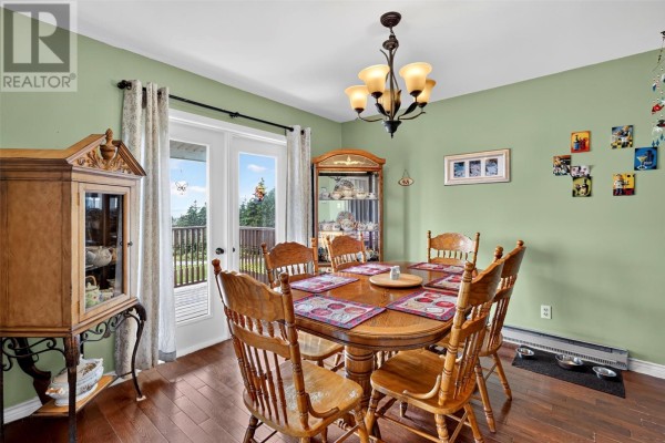Wooden deck with railing and chairs offering a view of the ocean and trees. - 109 Trinity South Highway, Cavendish