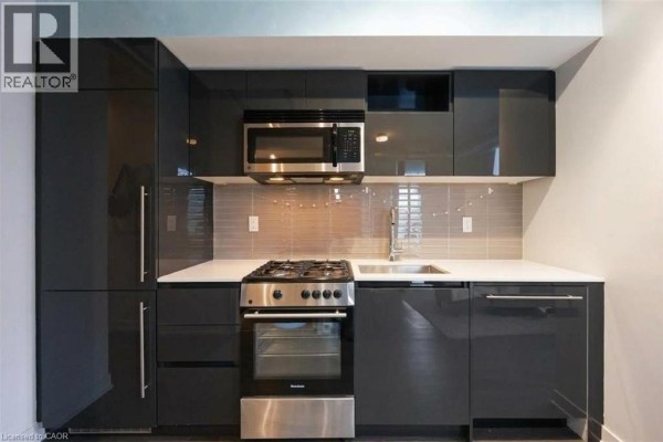 Close-up of a modern kitchen featuring dark grey cabinets, stainless steel appliances, and a white quartz countertop. - 109 Wolseley Street Unit# 204, Toronto