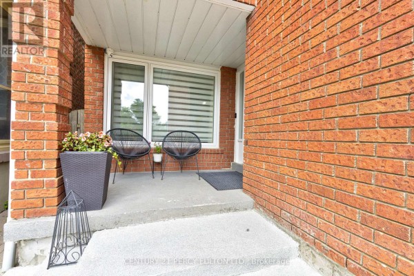 Front porch with two modern black chairs, a planter, and a red brick facade. - 109 Woodcroft Lane, Vaughan