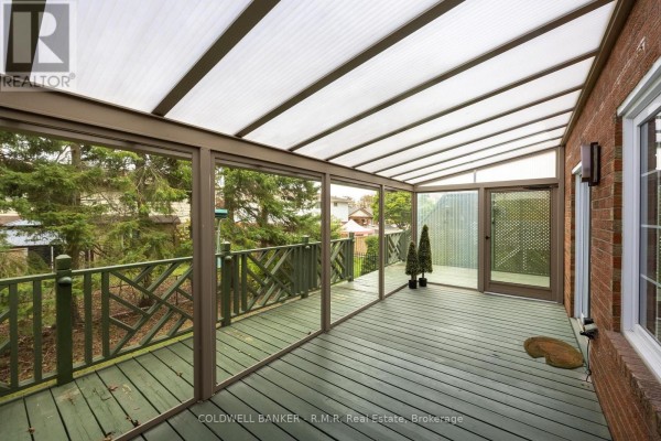 Enclosed sunroom with green wooden deck and views of trees. - 1090 Thimbleberry Circle, Oshawa