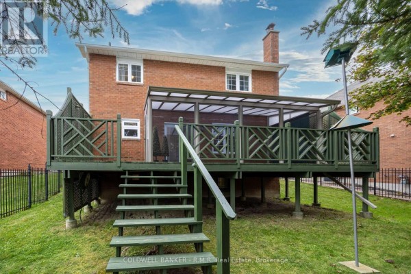 Rear view of brick house with green wooden deck and stairs. - 1090 Thimbleberry Circle, Oshawa