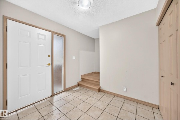 Interior entryway with beige tile flooring and a white door. - 10919 69 Av Nw, Edmonton