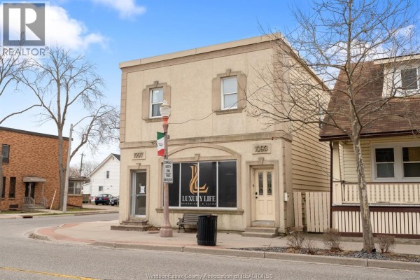 Exterior of a two-story beige building with arched storefront windows and light fixtures. - 1093-1097 Erie Street East, Windsor