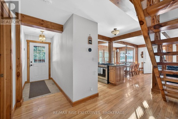 Entryway with white door, wood trim, and view into dining and kitchen area. - 1093b Two Loon Lane, Frontenac
