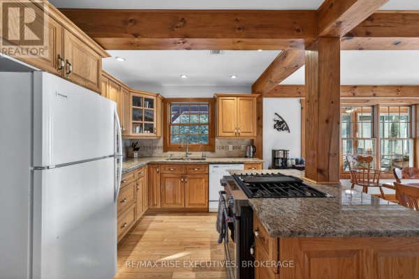 Kitchen with white refrigerator, wood cabinets, granite counters, and gas range. - 1093b Two Loon Lane, Frontenac